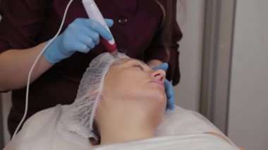 Professional beautician woman performs micronidling facial skin.