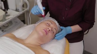 Professional beautician woman performs micronidling facial skin.