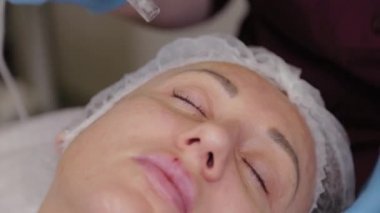Professional beautician woman performs micronidling facial skin.