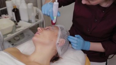 Professional beautician woman performs micronidling facial skin.