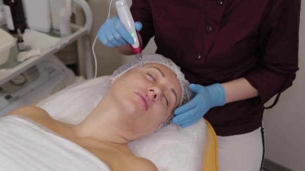 Professional beautician woman performs micronidling facial skin. — Stockvideo