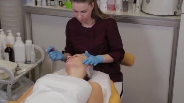 Professional beautician woman performs micronidling facial skin.