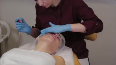 Professional beautician woman performs micronidling facial skin.