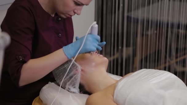 Professional beautician woman performs micronidling facial skin. — Stockvideo