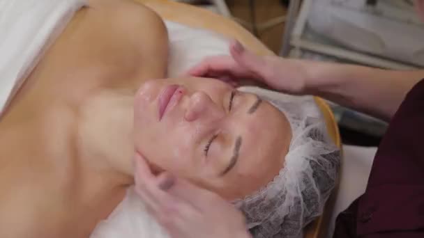Cosmétologue professionnelle femme faisant massage facial au client du salon de beauté . — Video