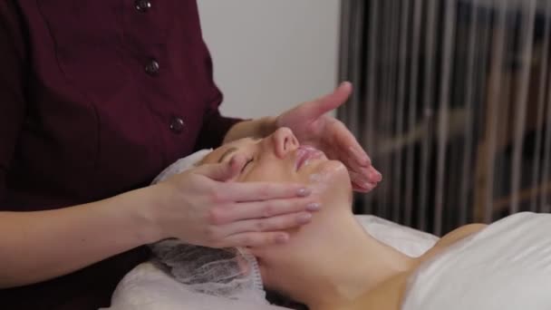 Cosmetóloga profesional haciendo masaje facial al cliente de salón de belleza . — Vídeo de stock