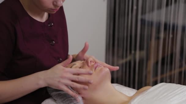 Professionelle Kosmetikerin macht Gesichtsmassage für Kunden des Schönheitssalons. — Stockvideo