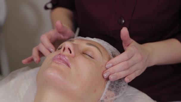 Profesjonalna kosmetolog kobieta robi masaż twarzy do klienta salonu piękności. — Wideo stockowe