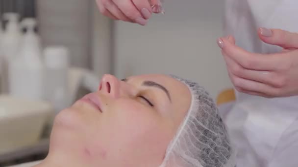 Professionele cosmetoloog die serum op de patiënten aanbrengt. — Stockvideo