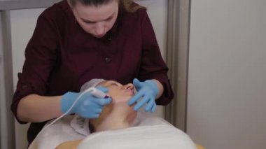 Professional beautician woman performs micronidling facial skin.