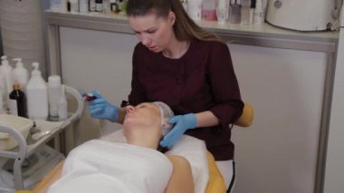 Professional beautician woman performs micronidling facial skin.
