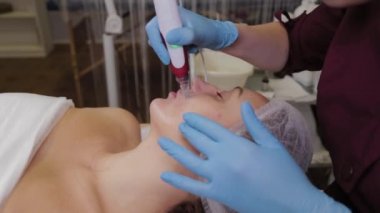 Professional beautician woman performs micronidling facial skin.