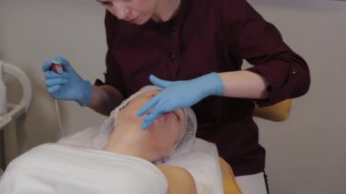 Professional beautician woman performs micronidling facial skin.