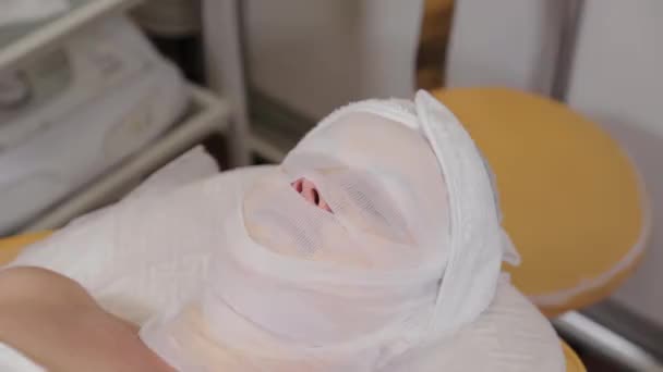 Femme patiente couche avec des bandages sur son visage dans un salon de beauté . — Video