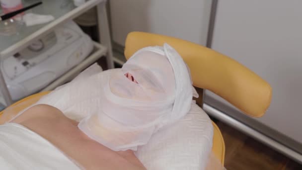 Vrouw patiënt ligt met verband op haar gezicht in een schoonheidssalon. — Stockvideo