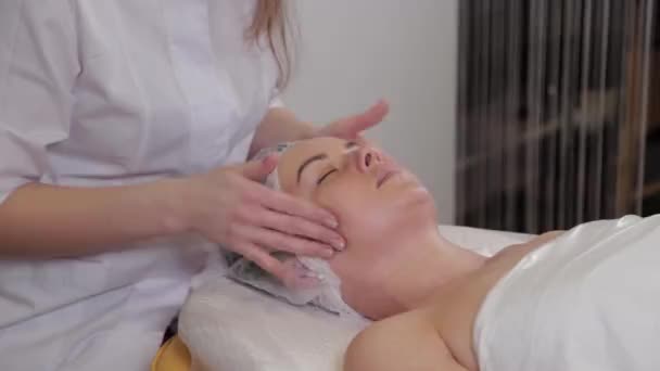 Profesionální kosmetička žena dělá masáž obličeje klientovi salonu krásy. — Stock video