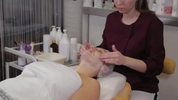 Un estetista professionista lava il viso dei pazienti con sapone liquido e contemporaneamente massaggi . — Video Stock