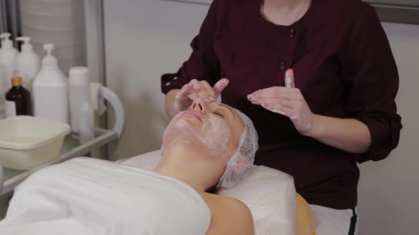 Eine professionelle Kosmetikerin wäscht das Gesicht der Patientinnen mit Flüssigseife und massiert gleichzeitig. — Stockvideo