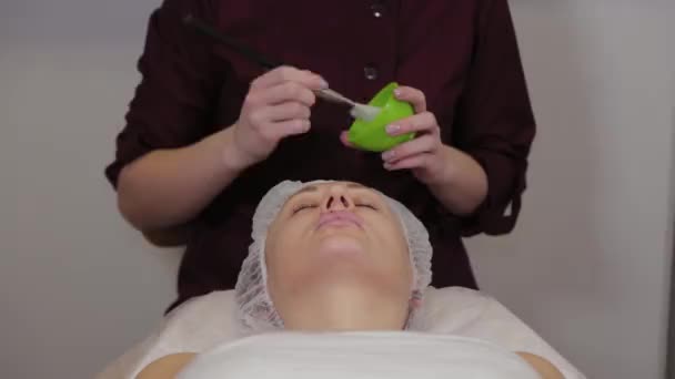 Professionele cosmetoloog vrouw zet een masker op het gezicht van de patiënt. — Stockvideo
