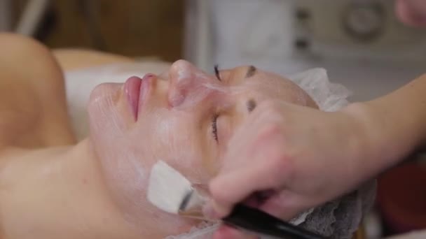 Cosmétologue professionnelle femme met un masque sur le visage du patient . — Video