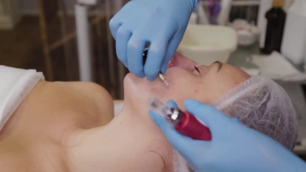 Donna cosmetologa professionista che applica il siero al viso dei pazienti . — Video Stock