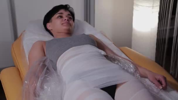 Cosmétologue professionnel femme enlève tous les bandages après la procédure d'emballage dans un salon de beauté . — Video