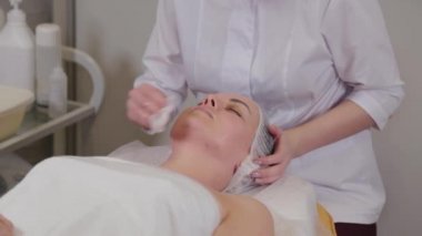 Professional beautician washes face to patient before procedure.
