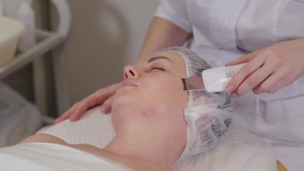 Cosmetóloga profesional haciendo limpieza facial ultrasónica al paciente. — Vídeos de Stock