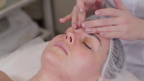 Cosmetologist profissional mulher fazendo massagem facial ao cliente de salão de beleza . — Vídeo de Stock