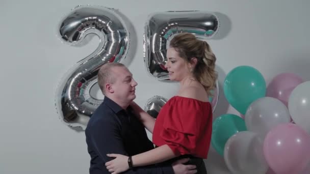 Beautiful man and woman cuddling near birthday balloons. — Stockvideo