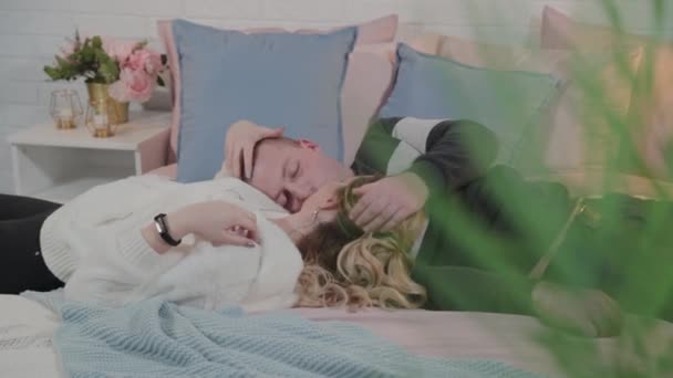 Schöner und junger Mann und Frau kuscheln im Bett. — Stockvideo