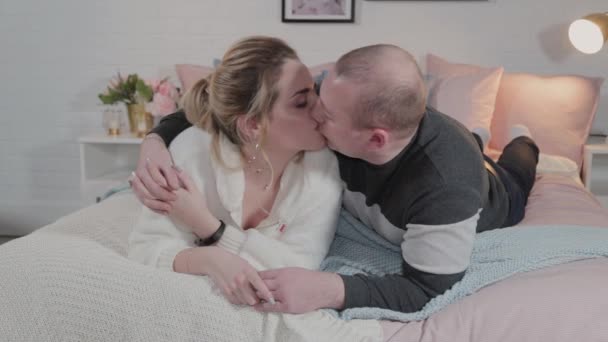 Hermoso y joven hombre y mujer abrazándose en la cama . — Vídeos de Stock