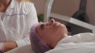 Profesyonel güzellik uzmanı pamuk pedlerle müşteriyle yüz yüze yıkanır.