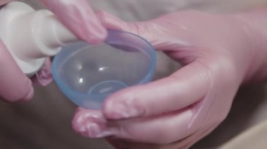 Profesyonel güzellik uzmanı karıştırmak için bir kabın içine maske koyar..