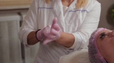 Profesyonel kozmetik uzmanı kadın ellerine lastik eldiven takıyor..