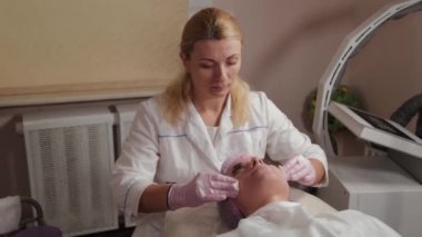 Profesyonel güzellik uzmanı pamuk pedlerle müşteriyle yüz yüze yıkanır.