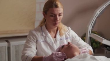 Profesyonel güzellik uzmanı pamuk pedlerle müşteriyle yüz yüze yıkanır.