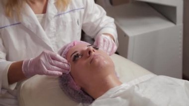 Profesyonel güzellik uzmanı pamuk pedlerle müşteriyle yüz yüze yıkanır.