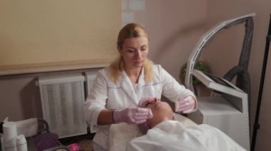 Profesyonel güzellik uzmanı pamuk pedlerle müşteriyle yüz yüze yıkanır.