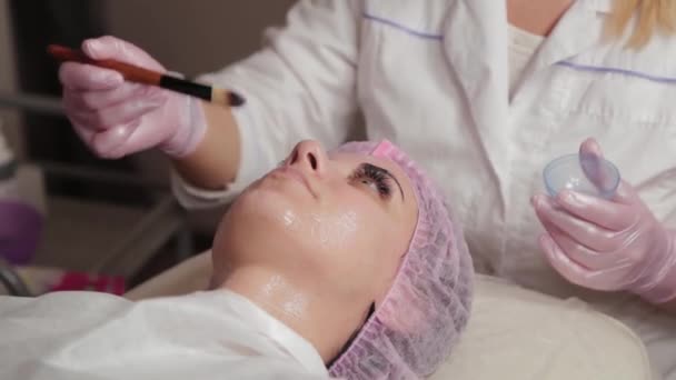 Professional beautician applying a mask on the face of the client with a brush. — 비디오