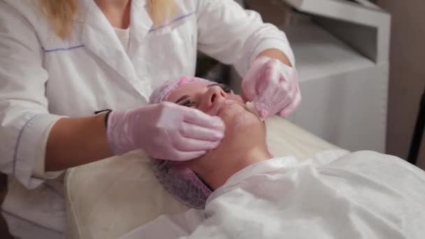 Esteticista profissional lava cara a cara com almofadas de algodão . — Vídeo de Stock