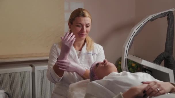 Επαγγελματική αισθητικός γυναίκα βάζει λαστιχένια γάντια στα χέρια της. — Αρχείο Βίντεο