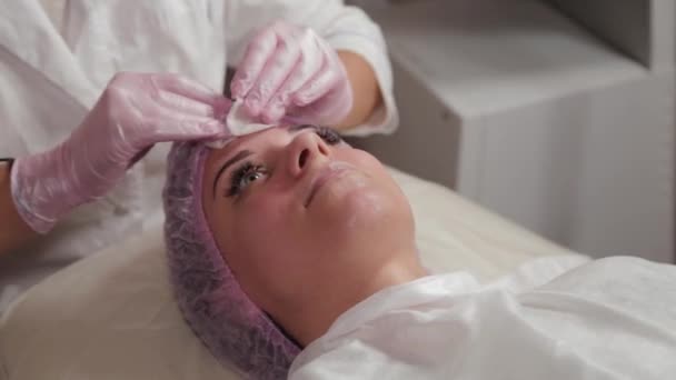 Profesionální kosmetička myje obličej ke klientovi vatovými podložkami. — Stock video