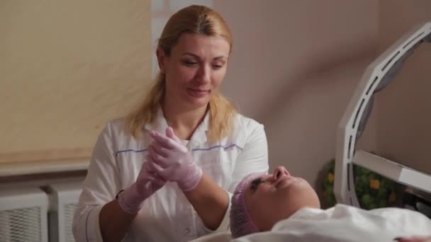 Donna cosmetologa professionista mette guanti di gomma sulle mani . — Video Stock