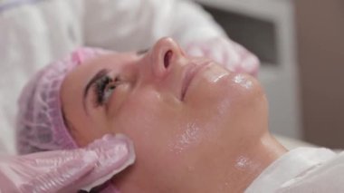 Profesyonel güzellik uzmanı pamuk pedlerle müşteriyle yüz yüze yıkanır.