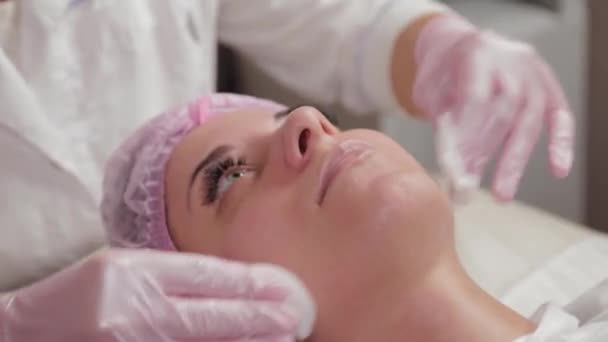 Professionell kosmetolog tvättar ansikte mot ansikte med bomullspads. — Stockvideo