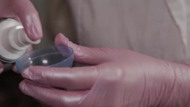 Profesyonel güzellik uzmanı karıştırmak için bir kabın içine maske koyar..