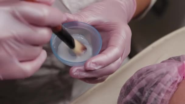 Professional beautician stirs a face mask with a brush. — Stock Video