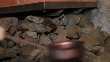 A man pours water on hot stones in a sauna.