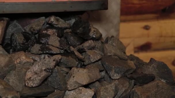 A man pours water on hot stones in a sauna. — Stock Video